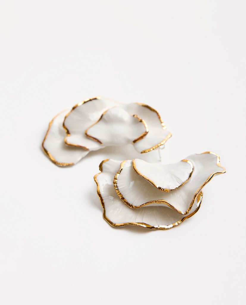 CLAVEL.
Pendientes de porcelana blanca, modelada a mano (pieza única) esmaltados en brillo, cocida a 1250 grados y lustrada en oro.Base de plata.PIEZA ÚNICA. El modelado a mano hace que sea imposible repetir un pétalo igual al otro. Estas piezas  son especiales por su unicidad.Medida pieza de porcelana:  6x3 cm (medidas aproximadas).
Piezas únicas de cerámica realizadas mediante un proceso artesanal
En La Polaca, cada creación nace de un cuidadoso proceso artesanal. Trabajamos la porcelana, gres y arcillas a mano, modelando, esmaltando, lustrando y dando forma a cada detalle con dedicación y sensibilidad. Cada pieza evoluciona de manera natural en el taller, siguiendo el ritmo del oficio cerámico.
El resultado es siempre una pieza única, con matices, texturas y pequeñas variaciones que le otorgan personalidad propia.
&nbsp;