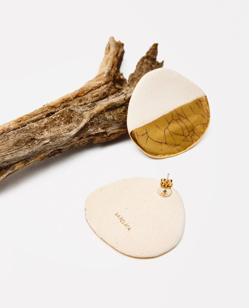 Colección TERRA.
- SUNA significa arena, la huella suave del tiempo sobre la tierra.Pendientes de gres lustrados en oro que evocan la textura cálida y sutil de los granos de arena. Cada pieza es única, uniendo lo natural y lo luminoso en un equilibrio perfecto. SUNA es un destello dorado nacido de la tierra.. 
&nbsp;Pendientes realizado en gres y cocido a 1220ºC. Lustrados en oro, modelados lisos.Tamaño aproximado 64x 4 cm.&nbsp;
Piezas únicas de cerámica realizadas mediante un proceso artesanal
En La Polaca, cada creación nace de un cuidadoso proceso artesanal. Trabajamos la porcelana, gres y arcillas a mano, modelando, esmaltando, lustrando y dando forma a cada detalle con dedicación y sensibilidad. Cada pieza evoluciona de manera natural en el taller, siguiendo el ritmo del oficio cerámico.
El resultado es siempre una pieza única, con matices, texturas y pequeñas variaciones que le otorgan personalidad propia.