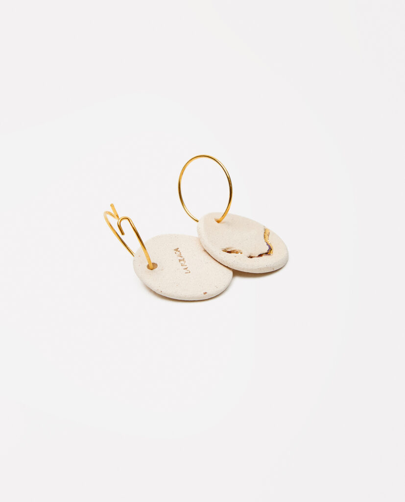 Colección TERRA.
- LEMI es memoria y luz. Pendientes de gres que conservan la huella de raíces, transformadas en delicados trazos de oro.Cada pieza es un testimonio de la conexión entre la tierra y la luz, entre lo ancestral y lo contemporáneo. LEMI es naturaleza hecha joya..
&nbsp;Pendientes realizado en gres y cocido a 1220º y  1260ºC. Lustrados en oro.Compuesto por pieza de cerámica circular plana de 2,3cm. Montados sobre aros de latón bañados en oro 16k.&nbsp;&nbsp;
Piezas únicas de cerámica realizadas mediante un proceso artesanal
En La Polaca, cada creación nace de un cuidadoso proceso artesanal. Trabajamos la porcelana, gres y arcillas a mano, modelando, esmaltando, lustrando y dando forma a cada detalle con dedicación y sensibilidad. Cada pieza evoluciona de manera natural en el taller, siguiendo el ritmo del oficio cerámico.
El resultado es siempre una pieza única, con matices, texturas y pequeñas variaciones que le otorgan personalidad propia.