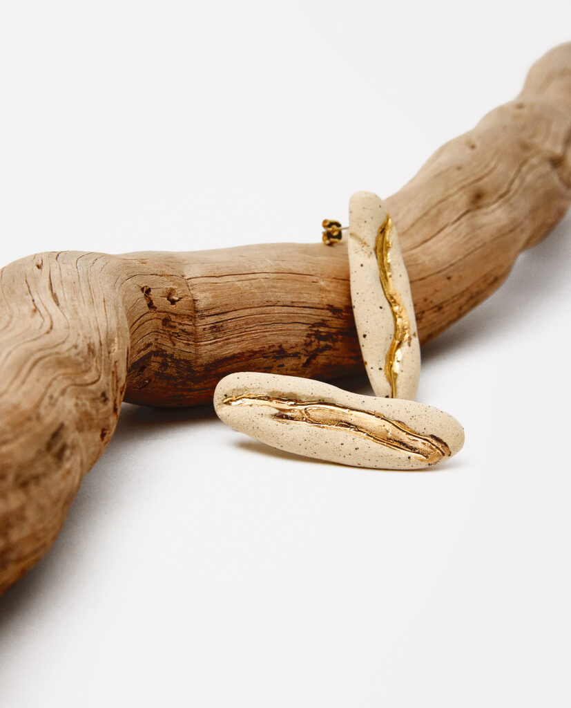 Colección TERRA.
- IMA es esencia en movimiento. Pendientes de cerámica que nacen de la tierra y el fuego, donde cada curva y textura cuenta una historia única.IMA es delicadeza, autenticidad y la belleza de lo imperfecto hecha joya..
&nbsp;Pendientes  realizado en gres y cocido a 1220ºC y 1260ºC. Lustrados en oro.Largo de la pieza 5 x 1,3cm.&nbsp;&nbsp;
Piezas únicas de cerámica realizadas mediante un proceso artesanal
En La Polaca, cada creación nace de un cuidadoso proceso artesanal. Trabajamos la porcelana, gres y arcillas a mano, modelando, esmaltando, lustrando y dando forma a cada detalle con dedicación y sensibilidad. Cada pieza evoluciona de manera natural en el taller, siguiendo el ritmo del oficio cerámico.
El resultado es siempre una pieza única, con matices, texturas y pequeñas variaciones que le otorgan personalidad propia.