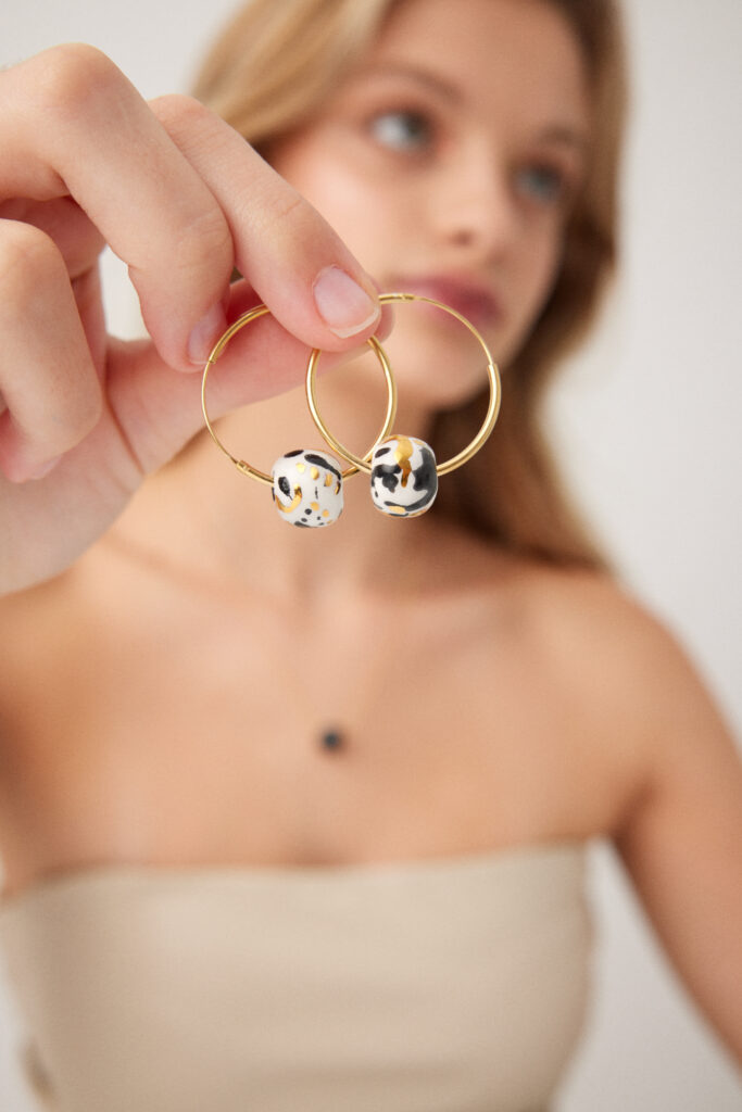 Colección CAREY.
- AURA surge del contraste entre la luz y la sombra, del equilibrio perfecto entre lo esencial y lo sagrado. Cada pendiente está modelado en cerámica blanca y pintado cuidadosamente con óxido negro, creando trazos que evocan movimiento, intuición y energía
&nbsp;Pendientes realizados en cerámica blanca, decoradas con óxido negro y  lustrados en oro.Compuesto por pieza de cerámica circular  de 0,8 cm ( medidas aproximadas). Montados sobre aros de plata bañados en  oro 16k.&nbsp;&nbsp;
Piezas únicas de cerámica realizadas mediante un proceso artesanal
En La Polaca, cada creación nace de un cuidadoso proceso artesanal. Trabajamos la porcelana, gres y arcillas a mano, modelando, esmaltando, lustrando y dando forma a cada detalle con dedicación y sensibilidad. Cada pieza evoluciona de manera natural en el taller, siguiendo el ritmo del oficio cerámico.
El resultado es siempre una pieza única, con matices, texturas y pequeñas variaciones que le otorgan personalidad propia.