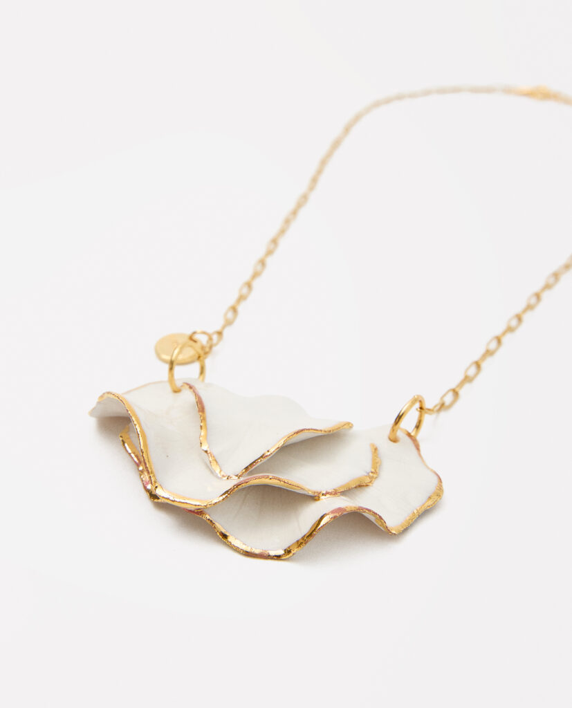 CLAVEL.
Collar de porcelana blanca, modelada a mano (pieza única) esmaltados en brillo, cocida a 1250 grados y lustrada en oro.Cadena de acero.Medida pieza de porcelana:  6 x 3,5cm.
Piezas únicas de cerámica realizadas mediante un proceso artesanal
En La Polaca, cada creación nace de un cuidadoso proceso artesanal. Trabajamos la porcelana, gres y arcillas a mano, modelando, esmaltando, lustrando y dando forma a cada detalle con dedicación y sensibilidad. Cada pieza evoluciona de manera natural en el taller, siguiendo el ritmo del oficio cerámico.
El resultado es siempre una pieza única, con matices, texturas y pequeñas variaciones que le otorgan personalidad propia.