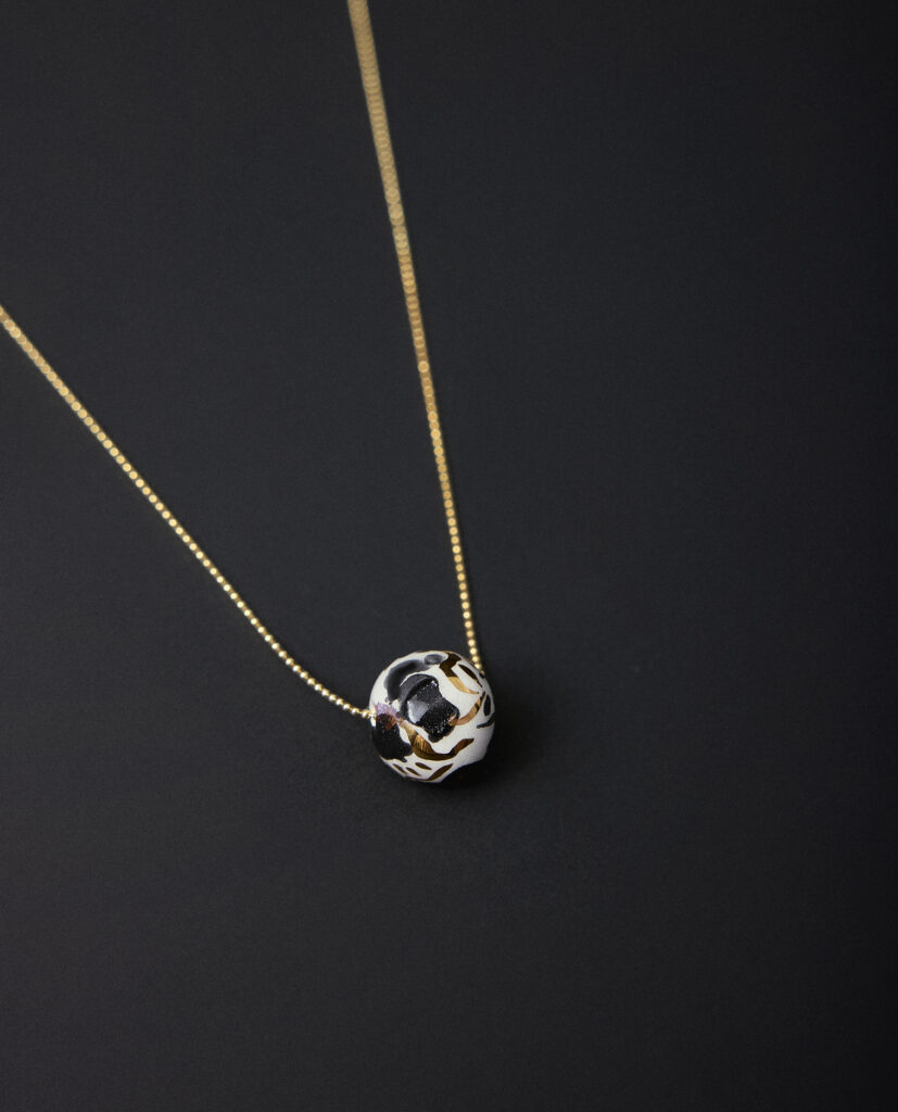 Colección CAREY.
- CAREY En cada curva de cerámica duerme la energía serena del gato carey, símbolo de intuición, juego y protección.
&nbsp;Collar realizado en cerámica blanca, lágrimas decoradas aleatoriamente con óxido negro y  lustrados en oro. PIEZA ÚNICA.Cadena de plata bañada en oro. Tamaño de la pieza cerámica: 1,3cm (aproximado).&nbsp;&nbsp;&nbsp;
Piezas únicas de cerámica realizadas mediante un proceso artesanal
En La Polaca, cada creación nace de un cuidadoso proceso artesanal. Trabajamos la porcelana, gres y arcillas a mano, modelando, esmaltando, lustrando y dando forma a cada detalle con dedicación y sensibilidad. Cada pieza evoluciona de manera natural en el taller, siguiendo el ritmo del oficio cerámico.
El resultado es siempre una pieza única, con matices, texturas y pequeñas variaciones que le otorgan personalidad propia.