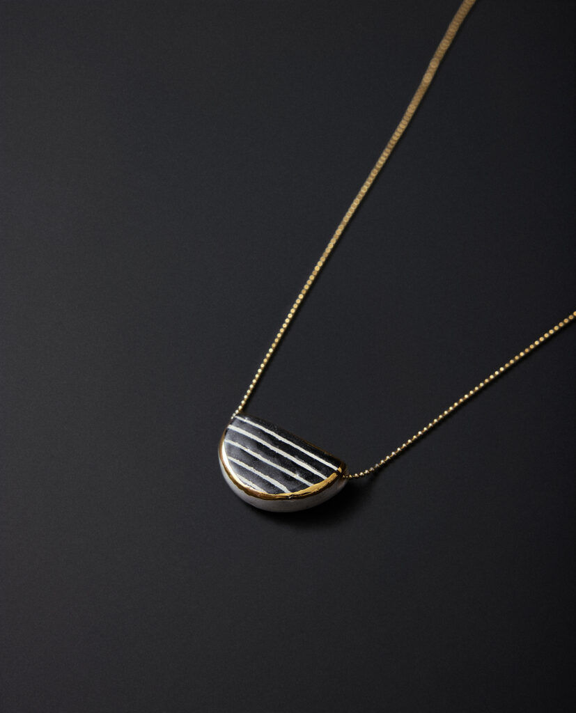 Colección CAREY.
- EOLAS nace como un amuleto para quienes confían en su voz interna. Modelado en cerámica y trabajado en un profundo negro, este collar encarna la quietud donde surge la claridad. Sobre su superficie el perfilado dorado destaca como un destello de revelación: ese instante en el que la intuición ilumina lo que el pensamiento aún no comprende.
&nbsp;Pendientes realizados en cerámica blanca, decoradas con óxido negro y  lustrados en oro.Compuesto por pieza de cerámica circular  de 0,8 cm ( medidas aproximadas). Montados sobre aros de plata bañados en  oro 16k.&nbsp;&nbsp;
Piezas únicas de cerámica realizadas mediante un proceso artesanal
En La Polaca, cada creación nace de un cuidadoso proceso artesanal. Trabajamos la porcelana, gres y arcillas a mano, modelando, esmaltando, lustrando y dando forma a cada detalle con dedicación y sensibilidad. Cada pieza evoluciona de manera natural en el taller, siguiendo el ritmo del oficio cerámico.
El resultado es siempre una pieza única, con matices, texturas y pequeñas variaciones que le otorgan personalidad propia.