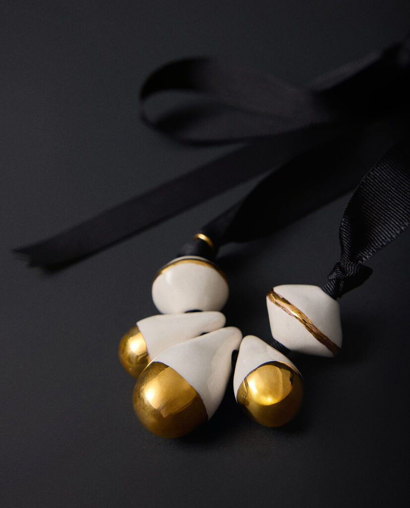 Colección CAREY.
- En este collar, la cerámica blanca guarda la fuerza de la luz sobre la noche. Es una pieza que habla de metamorfosis: del poder de convertir la sombra en brillo, lo simple en extraordinario.
&nbsp;Collar realizado en cerámica blanca  y  lustre de oro.Ancho total de la pieza 6cm ( medidas aproximadas). Montados sobre cinta negra.&nbsp;&nbsp;
Piezas únicas de cerámica realizadas mediante un proceso artesanal
En La Polaca, cada creación nace de un cuidadoso proceso artesanal. Trabajamos la porcelana, gres y arcillas a mano, modelando, esmaltando, lustrando y dando forma a cada detalle con dedicación y sensibilidad. Cada pieza evoluciona de manera natural en el taller, siguiendo el ritmo del oficio cerámico.
El resultado es siempre una pieza única, con matices, texturas y pequeñas variaciones que le otorgan personalidad propia.