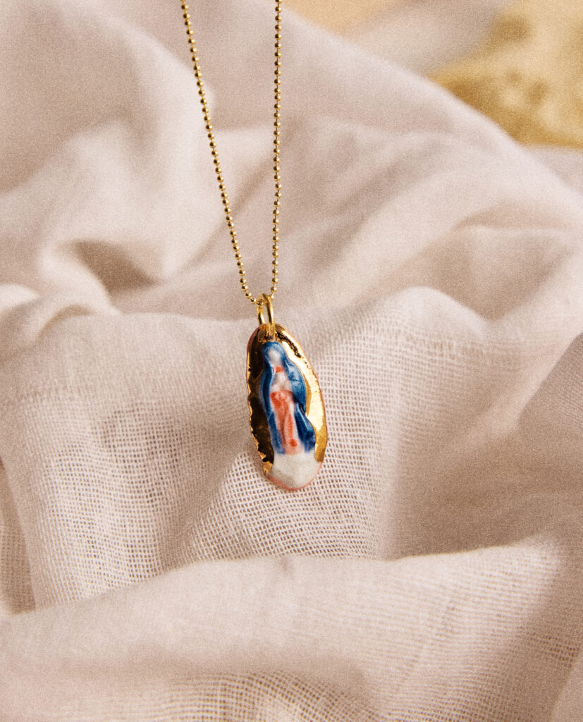 REGINA CAELI (Reina del cielo).
Collar Virgen de Guadalupe, modelada y pintada a mano, realizada en PORCELANA, cocida a 1230 grados y lustrada en ORO.Cadena de bolitas de plata bañada en oro 16k.Medidas de la medalla: 2,5 x 1,2 cm.Medidas longitud collar: 42cm.&nbsp;
Piezas únicas de cerámica realizadas mediante un proceso artesanal
En La Polaca, cada creación nace de un cuidadoso proceso artesanal. Trabajamos la porcelana, gres y arcillas a mano, modelando, esmaltando, lustrando y dando forma a cada detalle con dedicación y sensibilidad. Cada pieza evoluciona de manera natural en el taller, siguiendo el ritmo del oficio cerámico.
El resultado es siempre una pieza única, con matices, texturas y pequeñas variaciones que le otorgan personalidad propia.