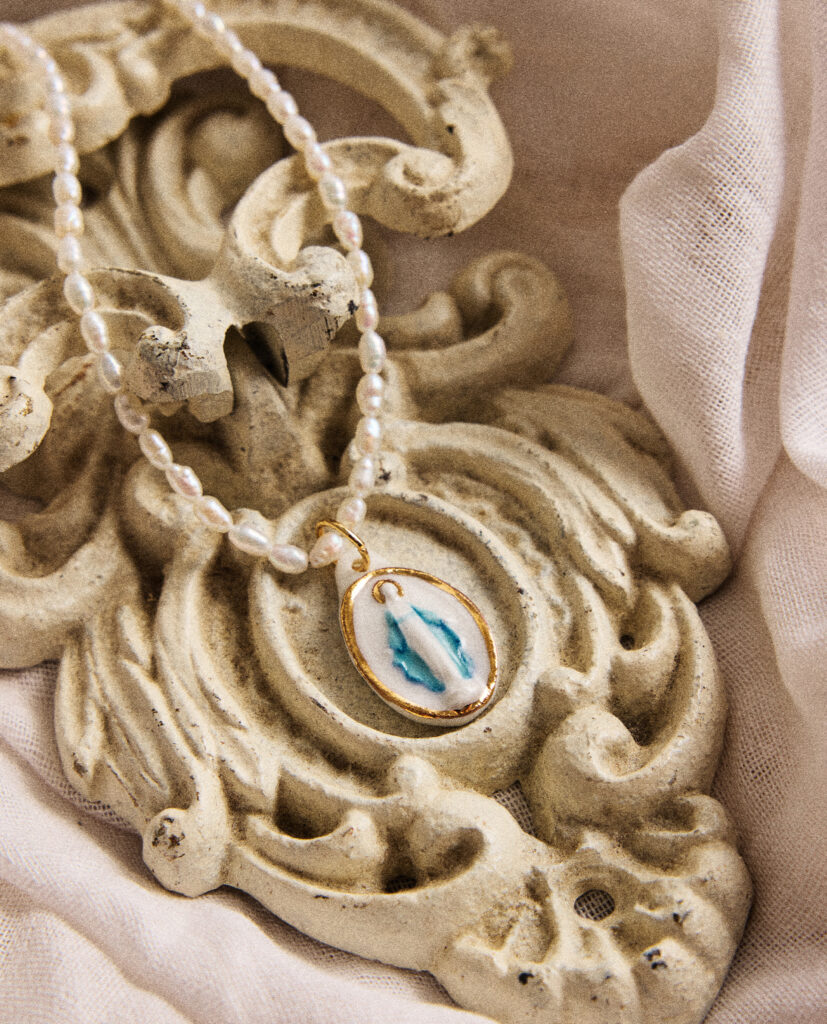 REGINA CAELI (Reina del cielo).
Collar medalla de la Milagrosa, modelada y pintada a mano, realizada en PORCELANA, cocida a 1230 grados y lustrada en ORO.Collar de perla natural forma orgánica 5mm.Medidas de la medalla: 1,6 x 2,5 cm.Medidas longitud collar de perlas: 42cm.&nbsp;
Piezas únicas de cerámica realizadas mediante un proceso artesanal
En La Polaca, cada creación nace de un cuidadoso proceso artesanal. Trabajamos la porcelana, gres y arcillas a mano, modelando, esmaltando, lustrando y dando forma a cada detalle con dedicación y sensibilidad. Cada pieza evoluciona de manera natural en el taller, siguiendo el ritmo del oficio cerámico.
El resultado es siempre una pieza única, con matices, texturas y pequeñas variaciones que le otorgan personalidad propia.