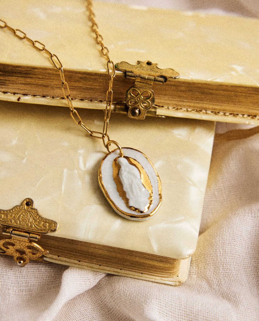 REGINA CAELI (Reina del cielo).
Collar medalla Virgen de Guadalupe, modelada y pintada a mano, realizada en PORCELANA, cocida a 1230 grados y lustrada en ORO.Cadena  eslabones de acero dorado.Medidas de la medalla: 2 x 3 cm.Medidas longitud collar: 42cm.&nbsp;
Piezas únicas de cerámica realizadas mediante un proceso artesanal
En La Polaca, cada creación nace de un cuidadoso proceso artesanal. Trabajamos la porcelana, gres y arcillas a mano, modelando, esmaltando, lustrando y dando forma a cada detalle con dedicación y sensibilidad. Cada pieza evoluciona de manera natural en el taller, siguiendo el ritmo del oficio cerámico.
El resultado es siempre una pieza única, con matices, texturas y pequeñas variaciones que le otorgan personalidad propia.
