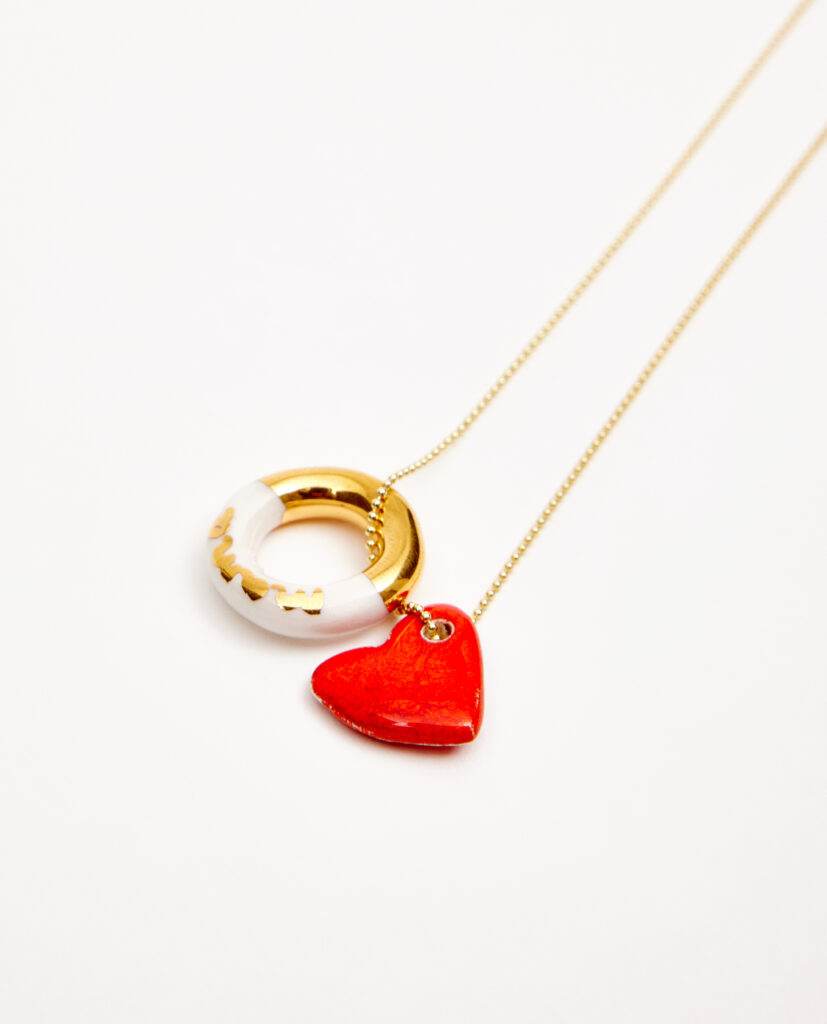 Cadena latón bañada  en oro. Aro de cerámica lustrado en oro texto mamá. Corazón de cerámica esmaltado en brillo.Diámetro aproximado del aro 15mm.  Largo de la cadena: 210mm.&nbsp;
Piezas únicas de cerámica realizadas mediante un proceso artesanal
En La Polaca, cada creación nace de un cuidadoso proceso artesanal. Trabajamos la porcelana, gres y arcillas a mano, modelando, esmaltando, lustrando y dando forma a cada detalle con dedicación y sensibilidad. Cada pieza evoluciona de manera natural en el taller, siguiendo el ritmo del oficio cerámico.
&nbsp;