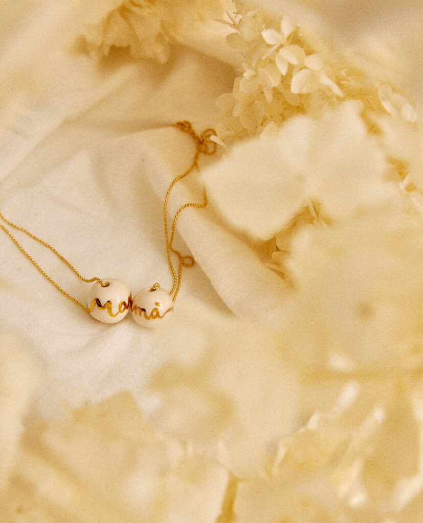 Bolita de  cerámica esmaltada en brillo lustrada en oro. Palabra mamá. Cadena de plata bañada en oro 16k.Diámetro de la bolita: 13mm (medidas aproximadas).&nbsp;
Piezas únicas de cerámica realizadas mediante un proceso artesanal
En La Polaca, cada creación nace de un cuidadoso proceso artesanal. Trabajamos la porcelana, gres y arcillas a mano, modelando, esmaltando, lustrando y dando forma a cada detalle con dedicación y sensibilidad. Cada pieza evoluciona de manera natural en el taller, siguiendo el ritmo del oficio cerámico.